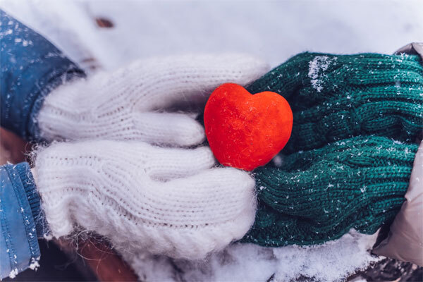 Image of hands holding a heart in the snow